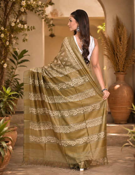 Back view of a woman displaying an olive cotton silk Batik saree with cream floral buti motifs and patterned pallu