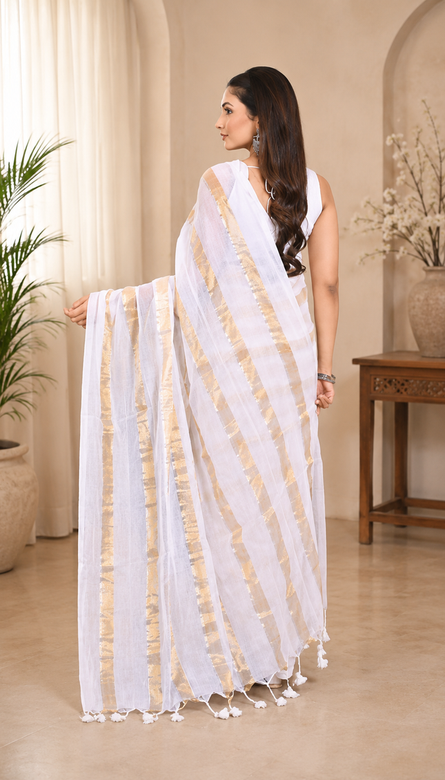 Back view of a woman wearing a white khadi saree with diagonal gold stripes and tassels