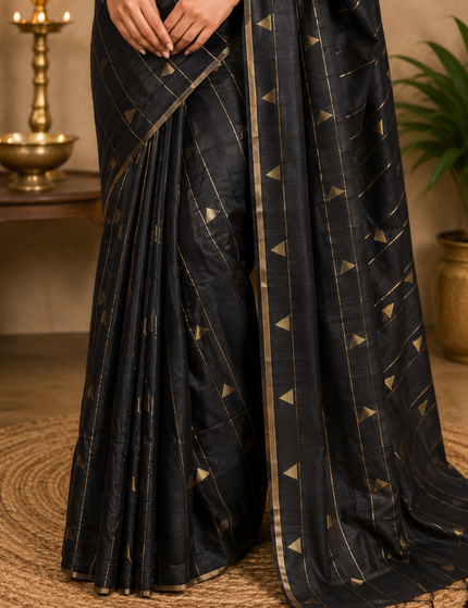 Close-up of black cotton saree drape showing gold triangular motifs and a tasselled pallu