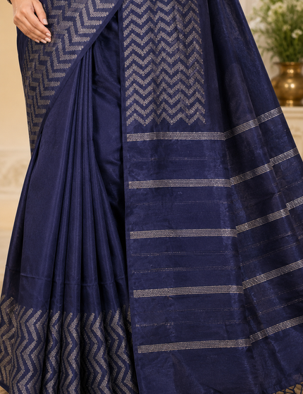 Close-up of a navy blue cotton Fishbone saree showing silver chevron motifs, pleats, striped pallu, woven texture, and tasseled edge.