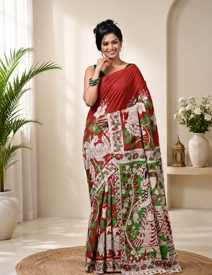 Close-up of a model wearing a red and green Kalamkari digital print cotton saree, highlighting floral motifs, birds and patterned fabric.