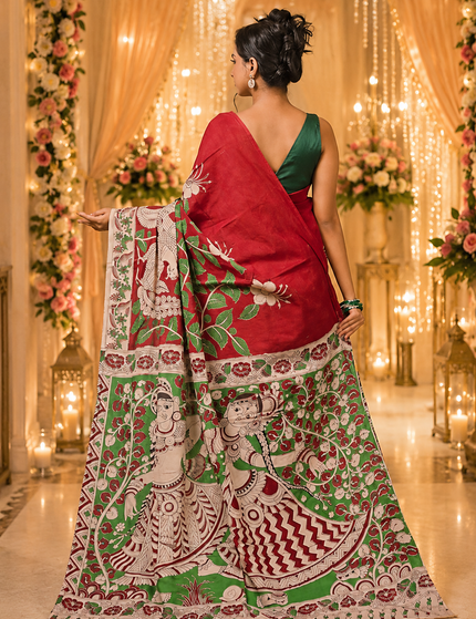 Model showing the back of a red and green Kalamkari digital print cotton saree, with a wide patterned pallu and floral border.