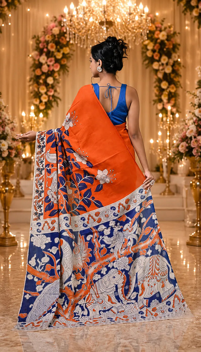 Model showing the back of an orange and navy Kalamkari digital print cotton saree, with a wide patterned pallu and decorative border.