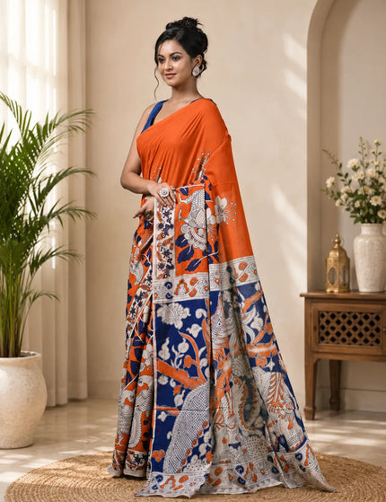Model in an orange and navy Kalamkari digital print cotton saree, three-quarter view showing printed pleats, figurative motifs and patterned border.
