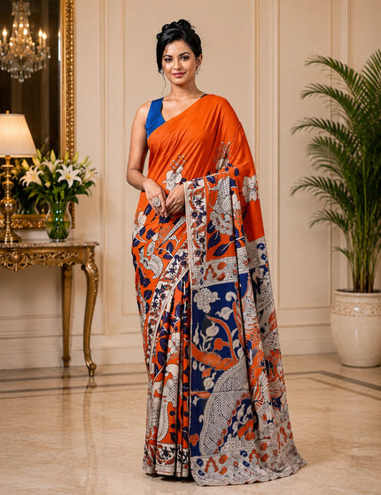 Model wearing an orange and navy Kalamkari digital print cotton saree, full-length view with white figurative motifs and patterned border.